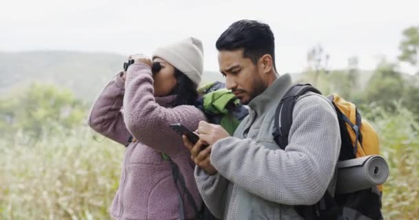 Paar, wandelen en mobiele telefoon met locatie zoeken in de natuur voor reizen met de online app voor vakantie. Avontuur, bossen en man met vrouw of trekking in de buitenlucht met tech voor vogels kijken in de winter - Video