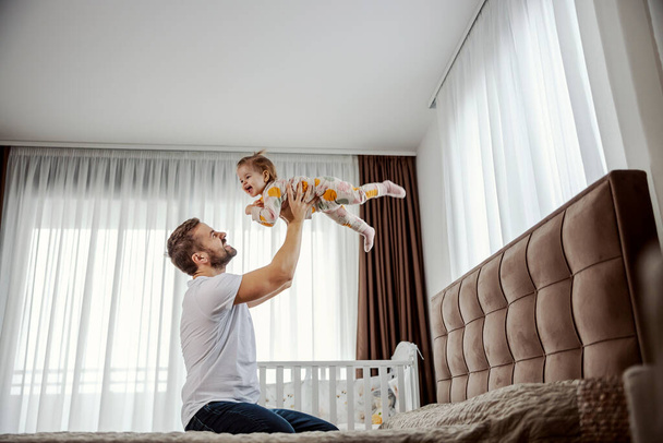 A father is lifting his daughter in the air and pretending she is flying while daughter is laughing and having fun. - Foto, Imagem