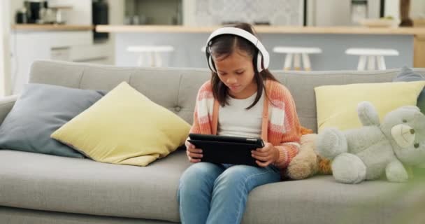 タブレット,音楽,姉妹の子供たちは,遠隔教育やゲームのために一緒に自宅のリビングルームのソファに座っています. テクノロジー,家族,そしてゲームをしながら子どもの絆を深めるeラーニング. - 映像、動画