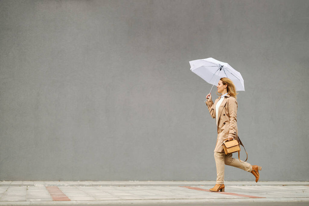 Жінка на підборах біжить на вулиці в дощовий осінній день і тікає від дощу. - Фото, зображення
