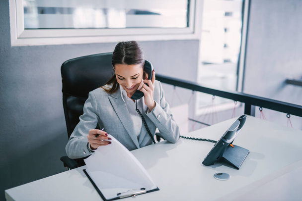 Женщина-ассистент назначает деловую встречу по телефону в корпоративной фирме. - Фото, изображение