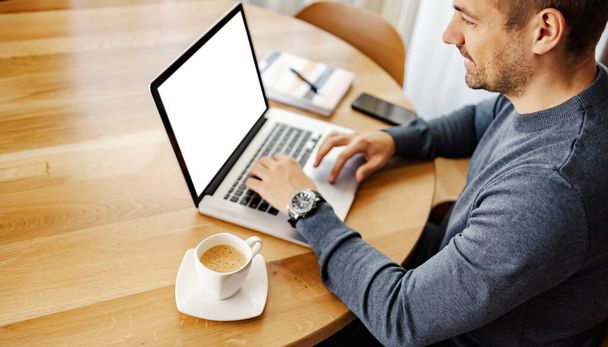 Um empresário casual senta-se em casa e digita no laptop enquanto bebe café. - Foto, Imagem