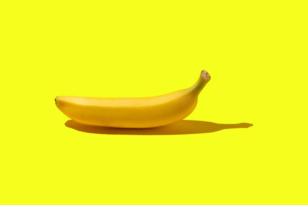 Жовтий стиглий банан лежить на жовтому тлі - Фото, зображення