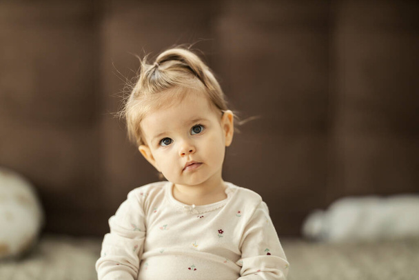 Una bambina perplessa sta guardando qualcosa mentre è seduta a casa. - Foto, immagini