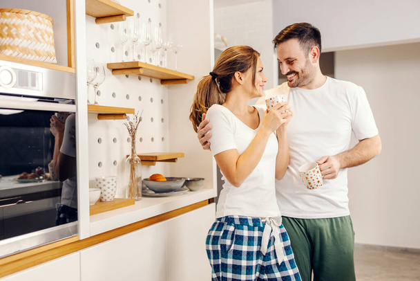 Pijamalı romantik bir çift mutfakta kahve içiyor.. - Fotoğraf, Görsel