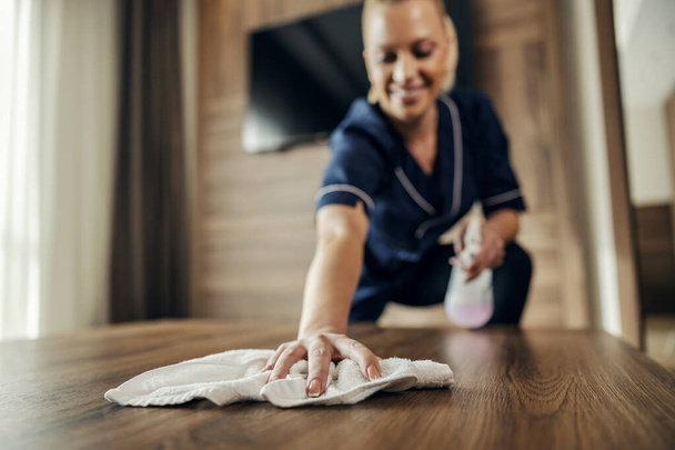 Selective focus on maid's hand cleaning floor in a hotel room with a detergent. - Photo, Image