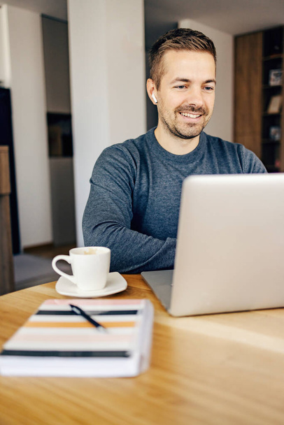 Ein glücklicher Geschäftsmann hat ein Online-Meeting mit Kollegen am Laptop, während er von zu Hause aus arbeitet. - Foto, Bild