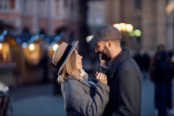 Pareja romántica abrazándose y abrazándose en la calle. Una joven pareja romántica feliz de pie en la calle, abrazándose y abrazándose en el día de San Valentín. - Foto, imagen