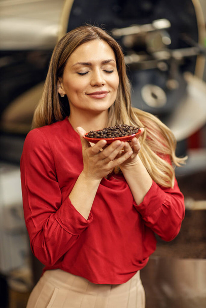 Une femme dans une usine de café parfumant des grains de café frais. - Photo, image