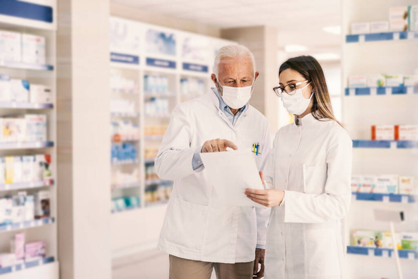 Travailleurs de pharmacie discutant et regardant la prescription pendant le virus corona. - Photo, image