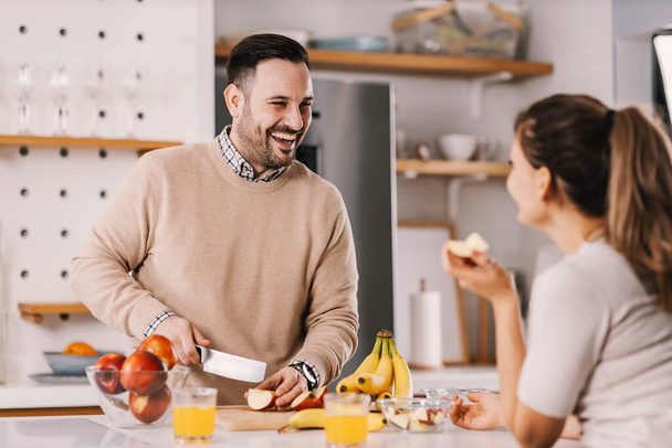 Una coppia felice che mangia frutta per uno spuntino sano a casa. - Foto, immagini