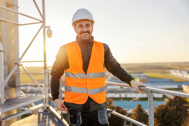 Портрет строителя, стоящего на высоте и улыбающегося в камеру. - Фото, изображение