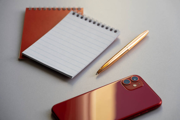 Concepto de negocio. Smartphone, bloc de notas y lápiz dorado en la mesa - Foto, imagen