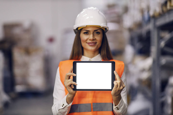Portrait of a satisfied storage worker showing tablet at the camera. - Photo, image