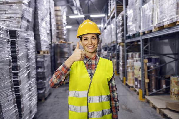 A warehouse worker is showing thumbs up for full storage and secured commodity reserves. - Foto, imagen