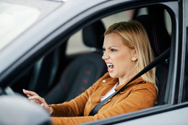 A furious woman in traffic jam. She is honking at other drivers - Photo, Image