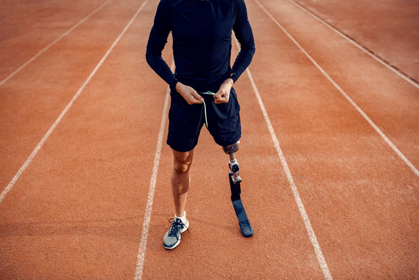 A runner with prosthetic leg preparing for workout on running track at stadium. - Photo, Image