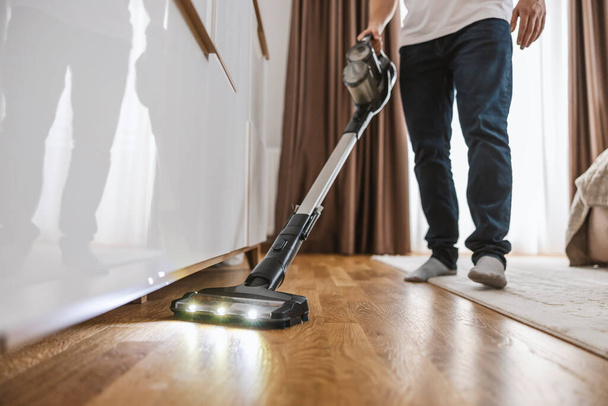 Selective focus on a vacuum cleaner vacuuming under the furniture. - Photo, Image