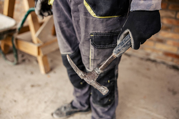 Gehakte foto van de hand van een bouwer die een hamer vasthoudt. Bouwen aan een huisconcept. - Foto, afbeelding