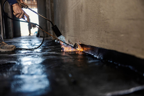 Обрезанная фотография домостроителя с помощью инструмента плавления для плавления битума. - Фото, изображение