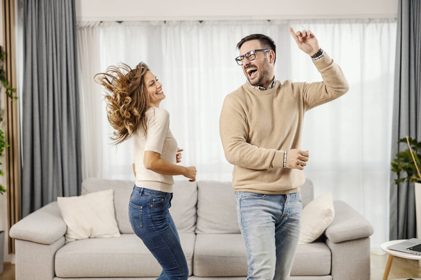 Ένα ευτυχισμένο ζευγάρι χορεύει και διασκεδάζει στο νέο τους διαμέρισμα.. - Φωτογραφία, εικόνα