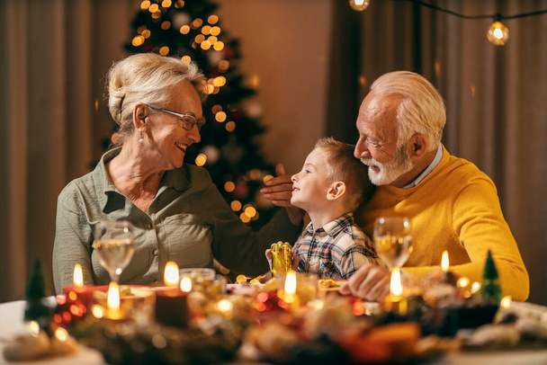 クリスマス・テーブルのクリスマス・テーブルでお祝いの祖父母と,クリスマスと新年のイブの孫.. - 写真・画像