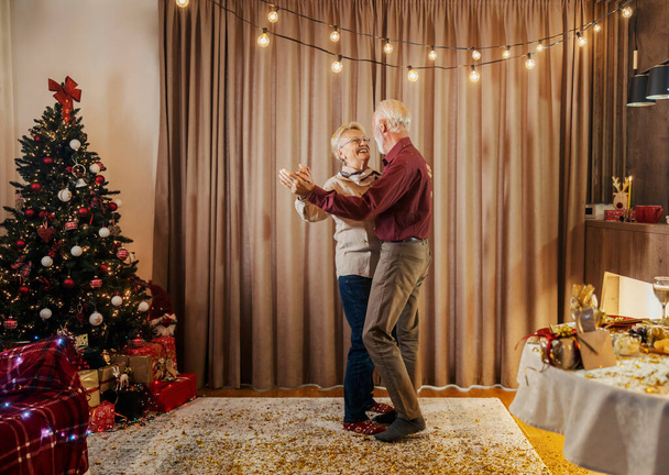 Ein glückliches, liebevolles Seniorenpaar tanzt an Weihnachten und Silvester zu Hause. - Foto, Bild