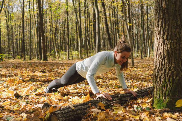 Bella ragazza che fa fitness in natura su una foresta soleggiata autunno. Corpo positivo, sport per le donne, armonia, stile di vita sano, amore per se stessi e benessere. - Foto, immagini