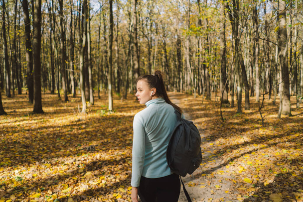 A girl in warm clothes walks through an autumn forest. Body positive, sports for women, harmony, healthy lifestyle, self-love and wellness. - Фото, изображение