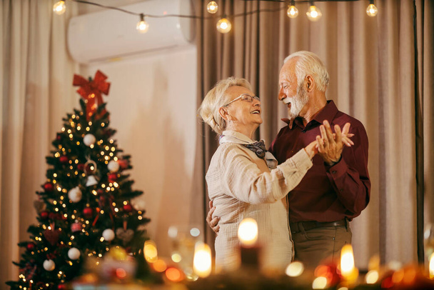 Uroczysta para seniorów świętuje Boże Narodzenie i Sylwestra w domu podczas tańca. - Zdjęcie, obraz