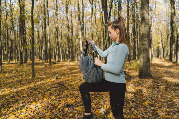 Dziewczyna w ciepłych ubraniach przechodzi przez jesienny las. Pozytywny wpływ na ciało, sport dla kobiet, harmonia, zdrowy tryb życia, miłość własna i wellness. - Zdjęcie, obraz