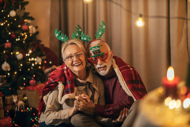 Portret van een senior paar in de liefde knuffelen en delen liefde op Kerst en oudejaarsavond, terwijl vieren. - Foto, afbeelding