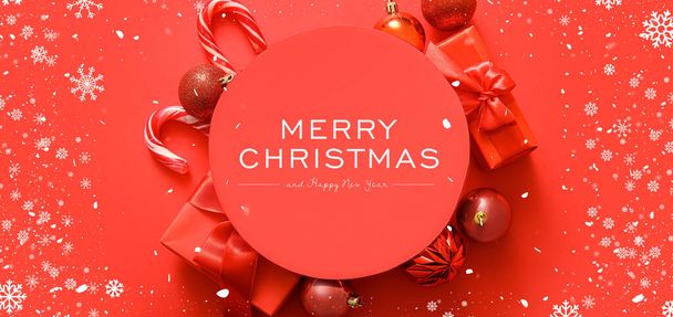 Вітальна листівка на Різдво та Новий рік з прикрасами та подарунками на червоному тлі - Фото, зображення