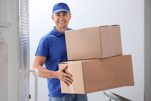 Mature courier with parcels in stairway - Photo, Image