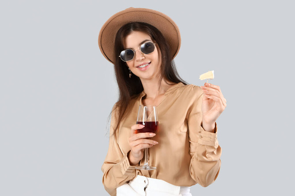Piękna młoda kobieta ze szklanką wina i sera na jasnym tle - Zdjęcie, obraz
