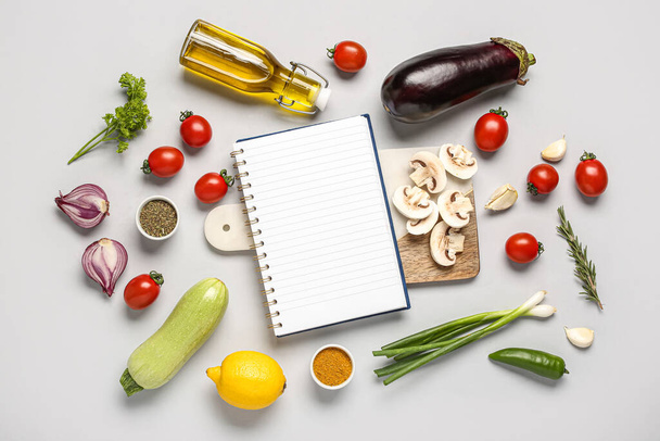 Composición con libro de recetas en blanco, verduras y especias sobre fondo gris - Foto, imagen