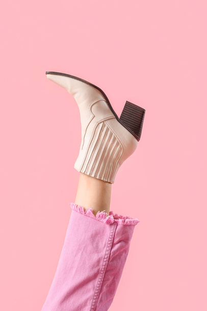 Нога молодої жінки в стильному бежевому шкіряному чоботі на рожевому фоні - Фото, зображення