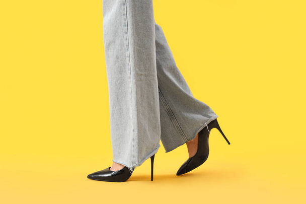 Legs of young woman in stylish black high heels on yellow background - Photo, Image