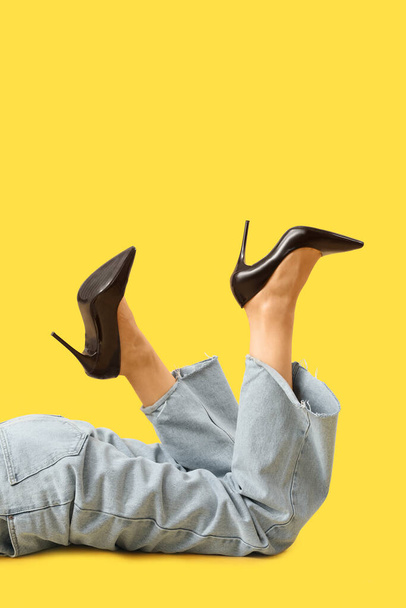 Ноги молодой женщины в стильных черных каблуках на жёлтом фоне - Фото, изображение