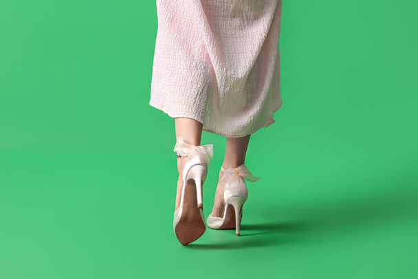 Legs of young woman in stylish pink high heels on green background - Photo, Image