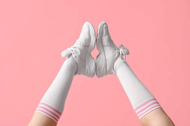Pembe arka planda şık beyaz spor ayakkabılı genç kadın bacakları. - Fotoğraf, Görsel
