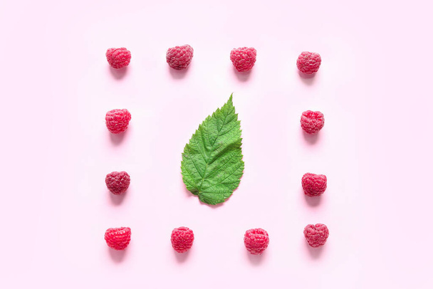 Frambuesas frescas maduras y hojas sobre fondo rosa - Foto, imagen