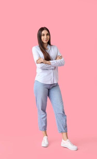 Mooie jonge vrouw in stijlvolle witte sneakers op roze achtergrond - Foto, afbeelding
