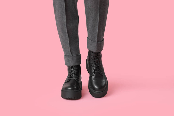 Nohy mladé ženy ve stylové černé kožené boty na růžovém pozadí - Fotografie, Obrázek