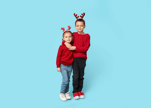 Cute little children in reindeer horns on blue background - Photo, Image