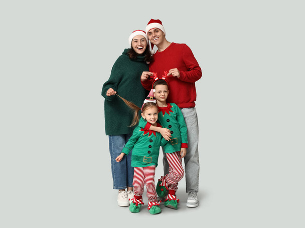 Happy family in Christmas clothes on grey background - Photo, Image