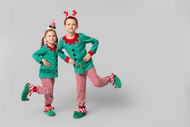 Cute little children dressed as elves dancing on grey background - Photo, Image