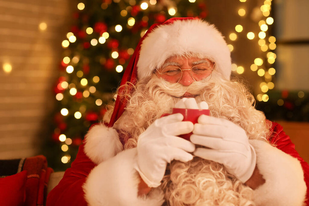 Noel Baba, Noel arifesinde evde lokumla sıcak çikolata içiyor. - Fotoğraf, Görsel