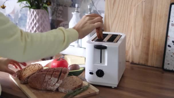 Genç bir kadın ekmek dilimlerini tost makinesine sokuyor. Kahvaltı konsepti. 4k görüntü. - Video, Çekim