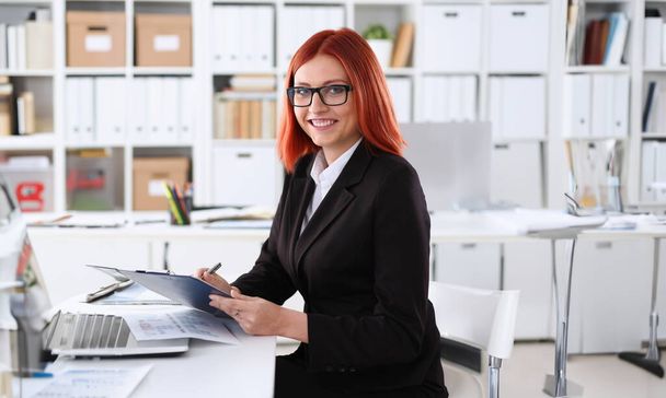 Geschäftsfrau am Arbeitsplatz im Büro Porträt in einem einfachen Anzug lächelt und blickt in die Kamera schafft einen Anschein von Arbeit und Erfolg schafft Vertrauen. - Foto, Bild